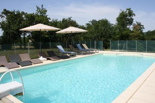 a swimming pool with chairs and umbrellas at Cottage de La Mothe in Marnac