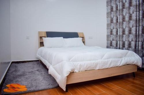 ein Schlafzimmer mit einem großen weißen Bett und einem Teppich in der Unterkunft Casamia Apartments in Nairobi