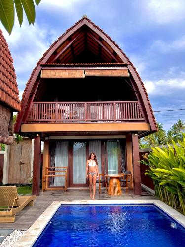 a woman standing in front of a house with a swimming pool at Bhumi Lovina Residence & Villa in Singaraja