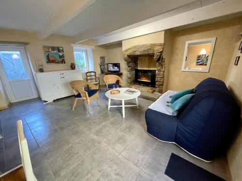 ein Wohnzimmer mit einem blauen Sofa und einem Kamin in der Unterkunft Authentique Penty au coeur du bourg in Roscanvel