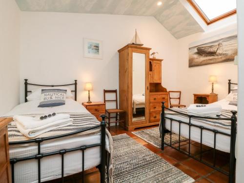 a bedroom with two beds and a mirror at The Shippen in Bude