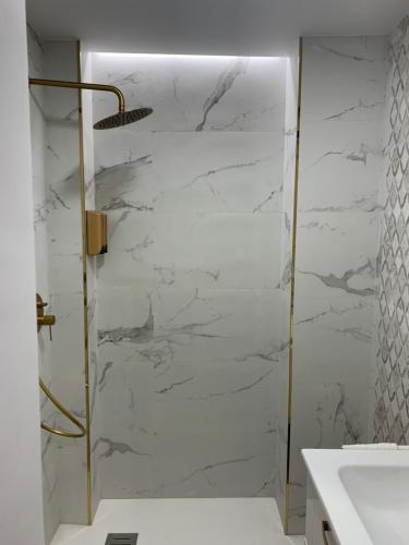 La salle de bains est pourvue d'une douche et d'un mur en marbre blanc. dans l'établissement APARTAMENTOS SAN PEDRO, à Grenade