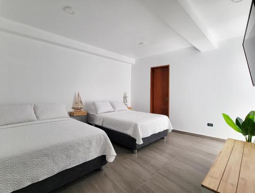 a white bedroom with two beds and a wooden table at ALTEA HOTEL - San Bartolo in San Bartolo