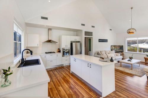an open kitchen and living room with white cabinets at Cumberland House in Katoomba