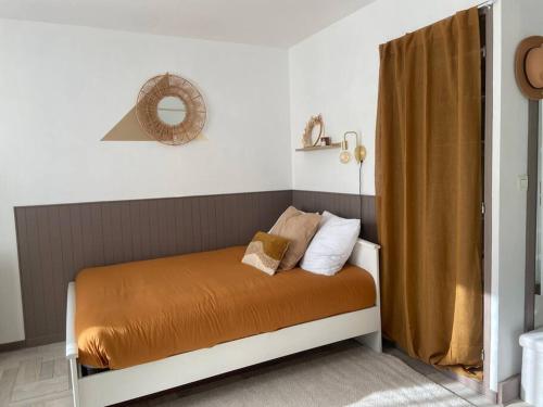 Bett mit orangefarbener Bettwäsche und Kissen in einem Zimmer in der Unterkunft Studio avec Balcon proche Gare in Bourg-en-Bresse