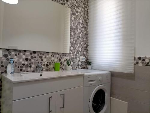 a bathroom with a sink and a washing machine at The Garden House alla Scala dei Turchi in Realmonte