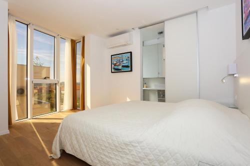 a bedroom with a white bed and large windows at Villa Art gallery apartments in Murter