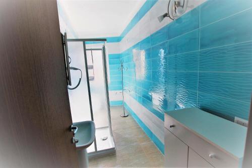 La salle de bains bleue est pourvue d'un lavabo et d'un miroir. dans l'établissement SHR Badesi, à Badesi