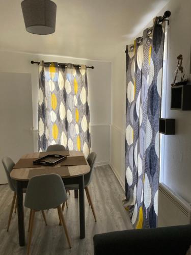 - une salle à manger avec une table, des chaises et des rideaux dans l'établissement Raiatea, au Tréport