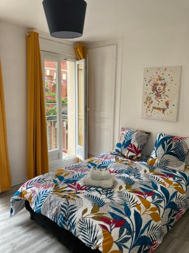 une chambre avec un lit avec une couette colorée et une fenêtre dans l'établissement Raiatea, au Tréport