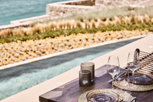 a table with wine glasses and a basket next to a pool at Amazon Mykonos Suites & Spa in Agios Ioannis Mykonos