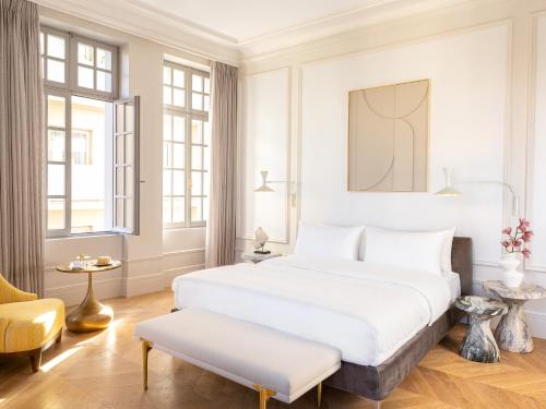 a white bedroom with a large bed and a chair at The Dolli at Acropolis, A Hotel to Live in Athens