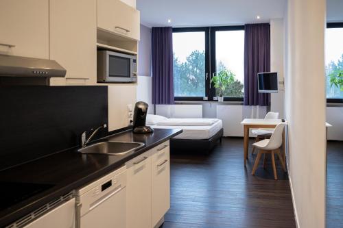 uma cozinha com um lavatório e uma sala de estar em apartmenthaus international em Munique