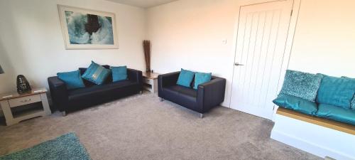 two black chairs in a living room with blue pillows at Station Heights in Rayleigh