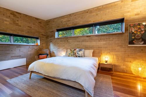 a brick walled bedroom with a bed and windows at Piano House in Blackheath