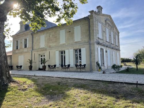 un grande edificio in pietra con sedie di fronte di Château de Neyran chambre d'hôtes & Spa a Soulac-sur-Mer