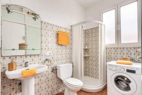 a bathroom with a toilet sink and a washing machine at Vista Arenal in Arenal d'en Castell