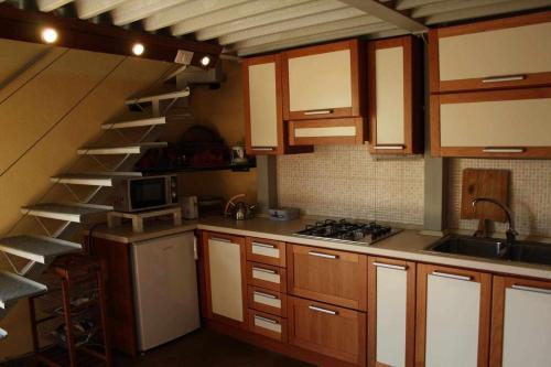 a kitchen with wooden cabinets and a spiral staircase at Domus Sol Aria in Castiadas