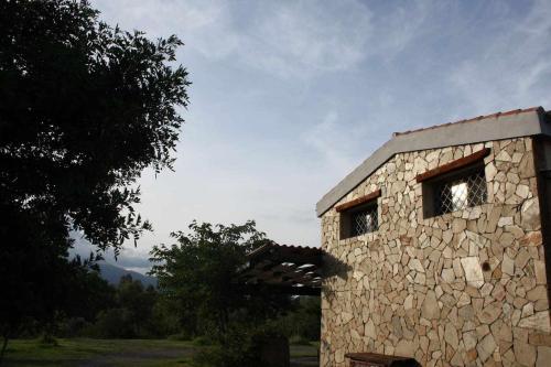 a stone building with two windows in a field at Domus Sol Aria in Castiadas