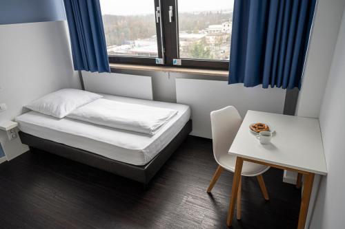 a small room with a bed and a table and a window at apartmenthaus international in Munich