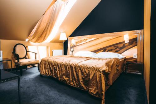 a bedroom with a large bed and a chair at Arensburg Boutique Hotel & Spa in Kuressaare