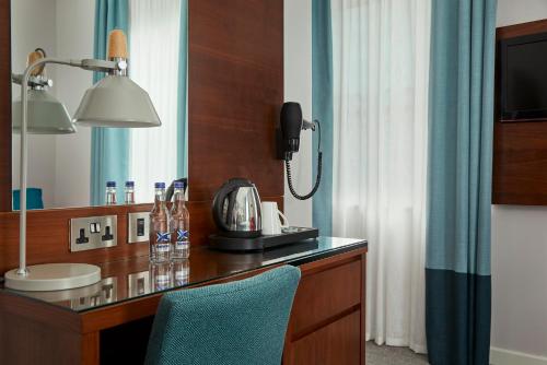 a bathroom with a desk with a sink and a phone at Seraphine Hammersmith Hotel in London