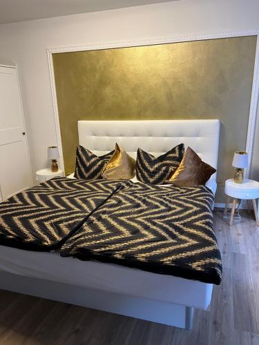 a bed with black and white sheets and gold pillows at Appartement im Funkenhöfchen in Pirna