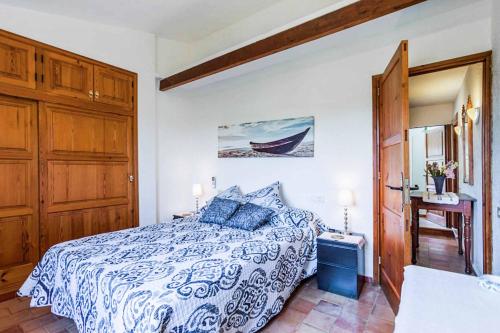 Schlafzimmer mit einem Bett mit einer blauen und weißen Bettdecke in der Unterkunft Can Font Roig in Pollença