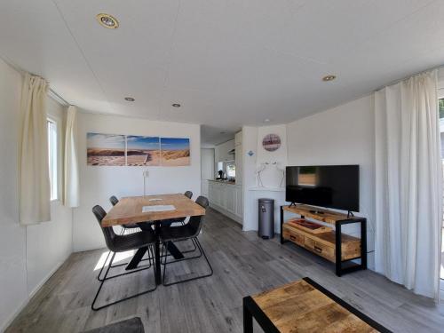 een woonkamer met een houten tafel en een televisie bij Chalet Texel DREaM nr. 17 op Chaletpark Bregkoog in De Koog