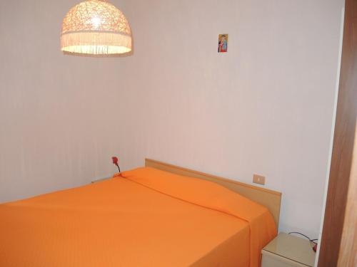 - une chambre avec un lit orange et une lumière dans l'établissement Warm two-room flat with terrace near the beach, à Bibione