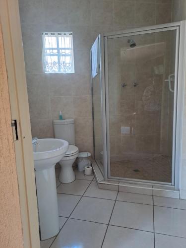 uma casa de banho com um chuveiro, um WC e um lavatório. em Amigos Bed & Breakfast - No loadshedding em Nelspruit
