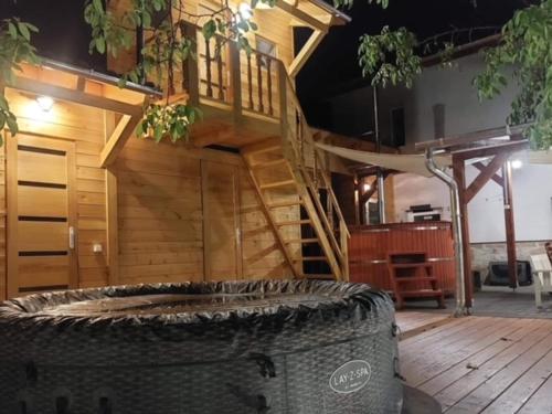 a wooden house with a wooden stairs and a large barrel at E-Tekergők Háza in Bükkzsérc