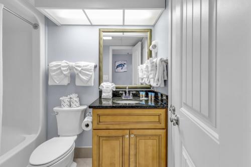 W łazience znajduje się umywalka, toaleta i lustro. w obiekcie Stunning Oceanfront Views w Pool - Atlantica Towers Condo w mieście Myrtle Beach