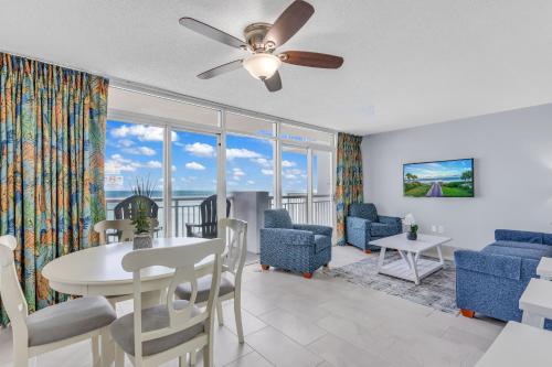 a living room with a table and chairs and a ceiling fan at Stunning Oceanfront Views w Pool - Atlantica Towers Condo in Myrtle Beach