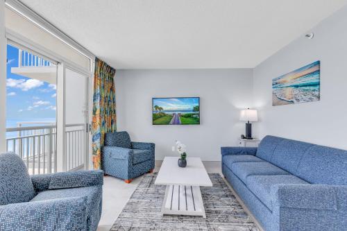 a living room with two blue couches and a table at Stunning Oceanfront Views w Pool - Atlantica Towers Condo in Myrtle Beach