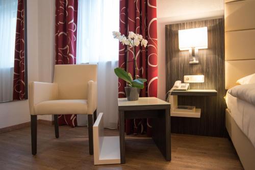 a room with a bed and a chair and a desk at Hotel Stadt Cuxhaven in Cuxhaven