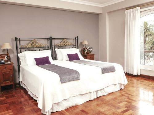 a bedroom with a large bed with white sheets and purple pillows at Solar De La Plaza in Salta