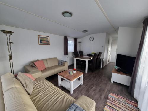 ein Wohnzimmer mit einem Sofa und einem Tisch in der Unterkunft Chalet MaMaMia nr. 54 op Chaletpark Bregkoog in De Koog