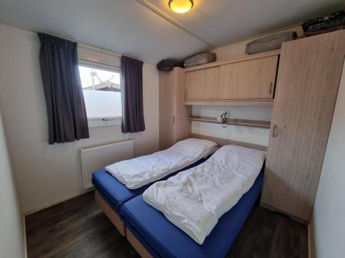 een kleine slaapkamer met een bed in een camper bij Chalet MaMaMia nr. 54 op Chaletpark Bregkoog in De Koog