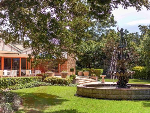 a statue in the middle of a park with a fountain at Mercure Hunter Valley Gardens in Pokolbin