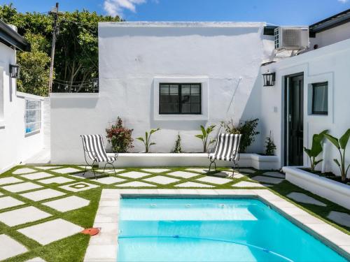 een achtertuin met een zwembad en twee stoelen en een huis bij The Belmont in Franschhoek