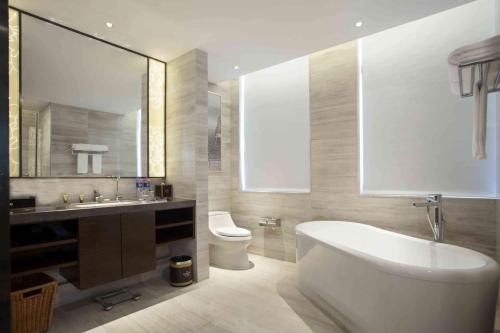 a bathroom with a tub and a toilet and a sink at Ramada Plaza by Wyndham Xi'an South in Xi'an