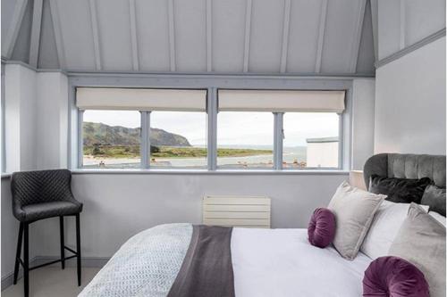 a bedroom with a bed and a chair and a window at Deganwy Tower Apartment in Deganwy