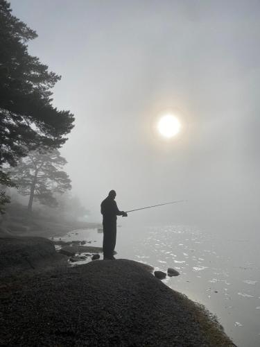 a man standing on the edge of a lake holding a fishing rod at Opushka in Vorobʼyëvka