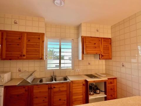 a kitchen with wooden cabinets and a sink and a window at Apto. S'aigua dolça 2 in Son Carrio