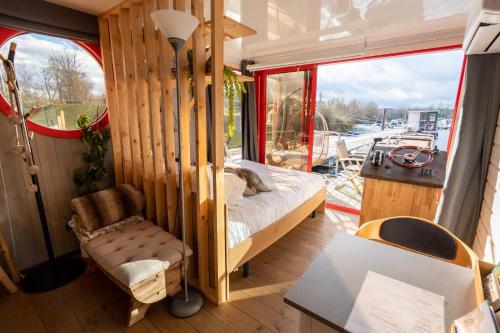 - une chambre avec un lit et une chaise dans un bateau dans l'établissement Escale Royale Port Ilon, à Saint-Martin-la-Garenne