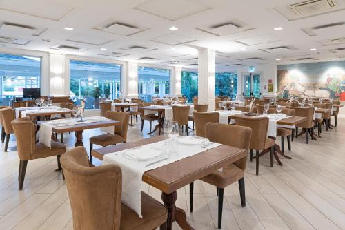 um restaurante com mesas, cadeiras e janelas em Mirabella Hotel em Mirabella Eclano