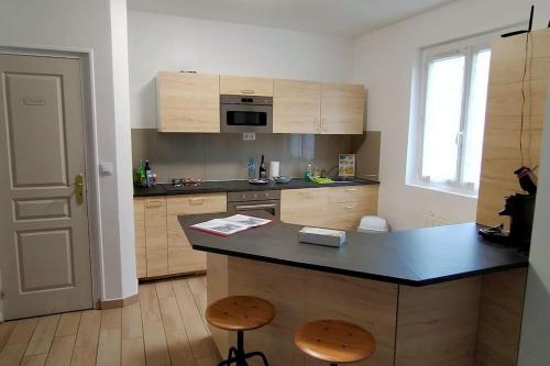 a kitchen with a counter and two stools in it at Chez F&K in Elbeuf