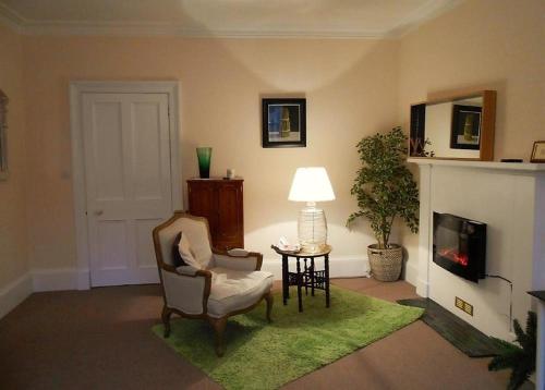 ein Wohnzimmer mit einem Kamin, einem Stuhl und einer Lampe in der Unterkunft Montrose Apartment in Selkirk