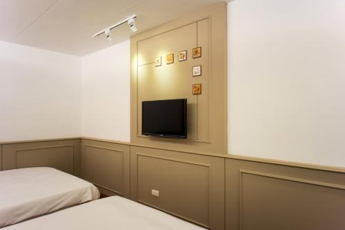 Habitación con cama y TV en la pared. en Bei Pin B&B en Nanwan